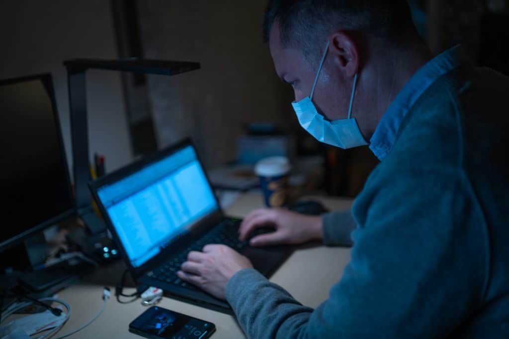 Man in mask searching online on computer