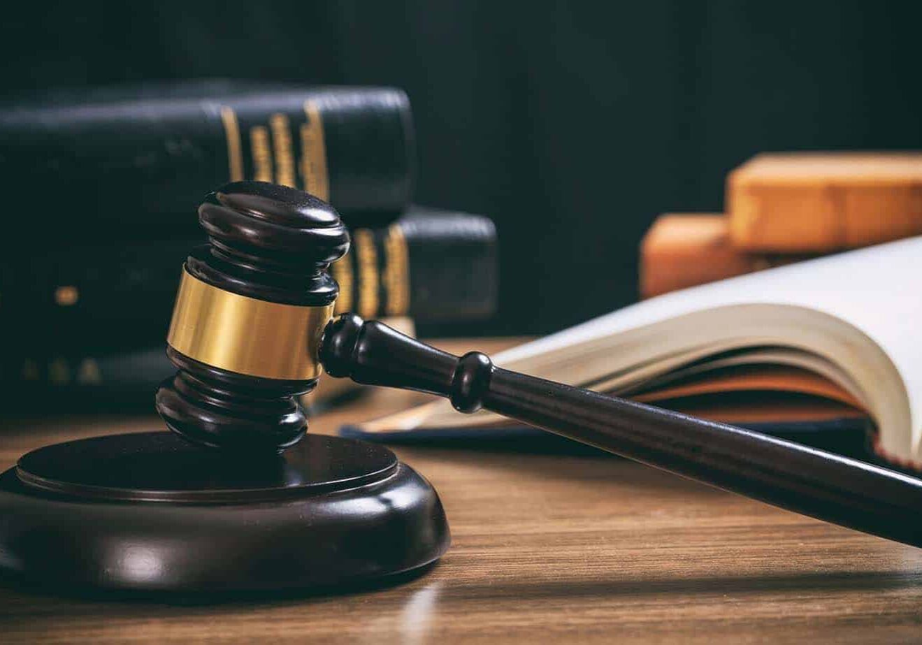 Law gavel on a wooden desk, law books background